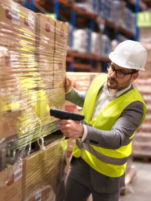 Male warehouse worker using bar code scanner to analyze newly arrived goods for further placement in storage department.